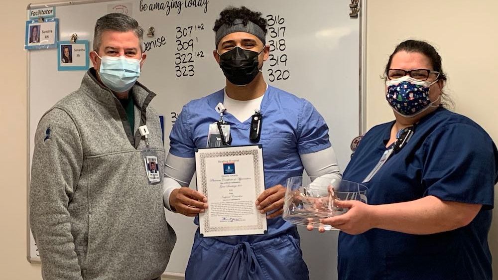 President and two nurses holding an award.