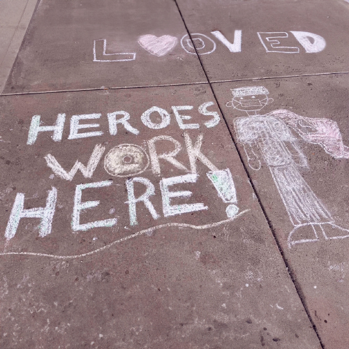 Sidewalk chalk artwork depicting healthcare workers and "Heros Work Here" at Pottstown Hospital drawn by volunteers students at Perkiomen Valley School District students 
