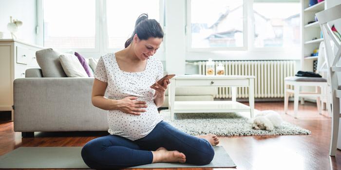 pregnant woman stretching while looking at phone