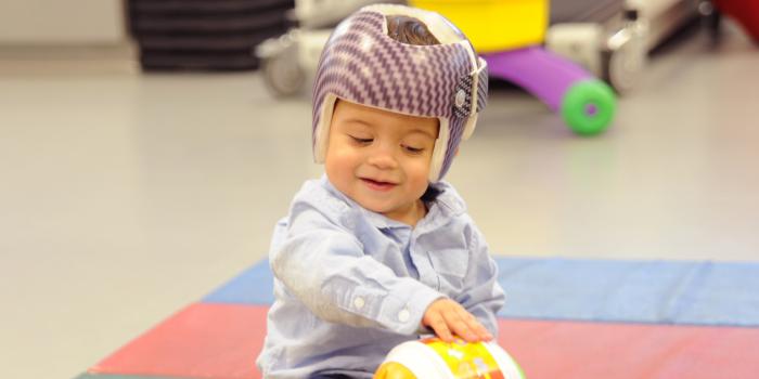 baby with helmet touching ball