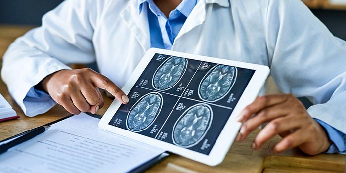 Medical provider pointing to brain images on a tablet device